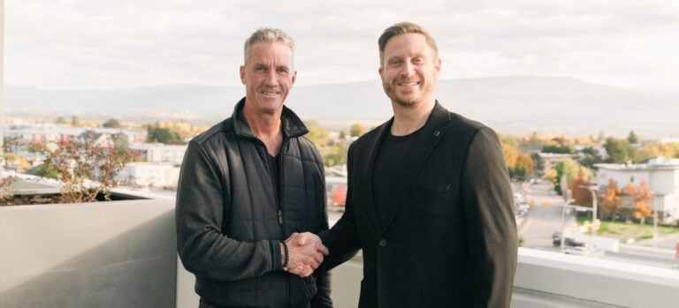 Two men shaking hands on a terrace to celebrate the Ace and Sutton partnership.