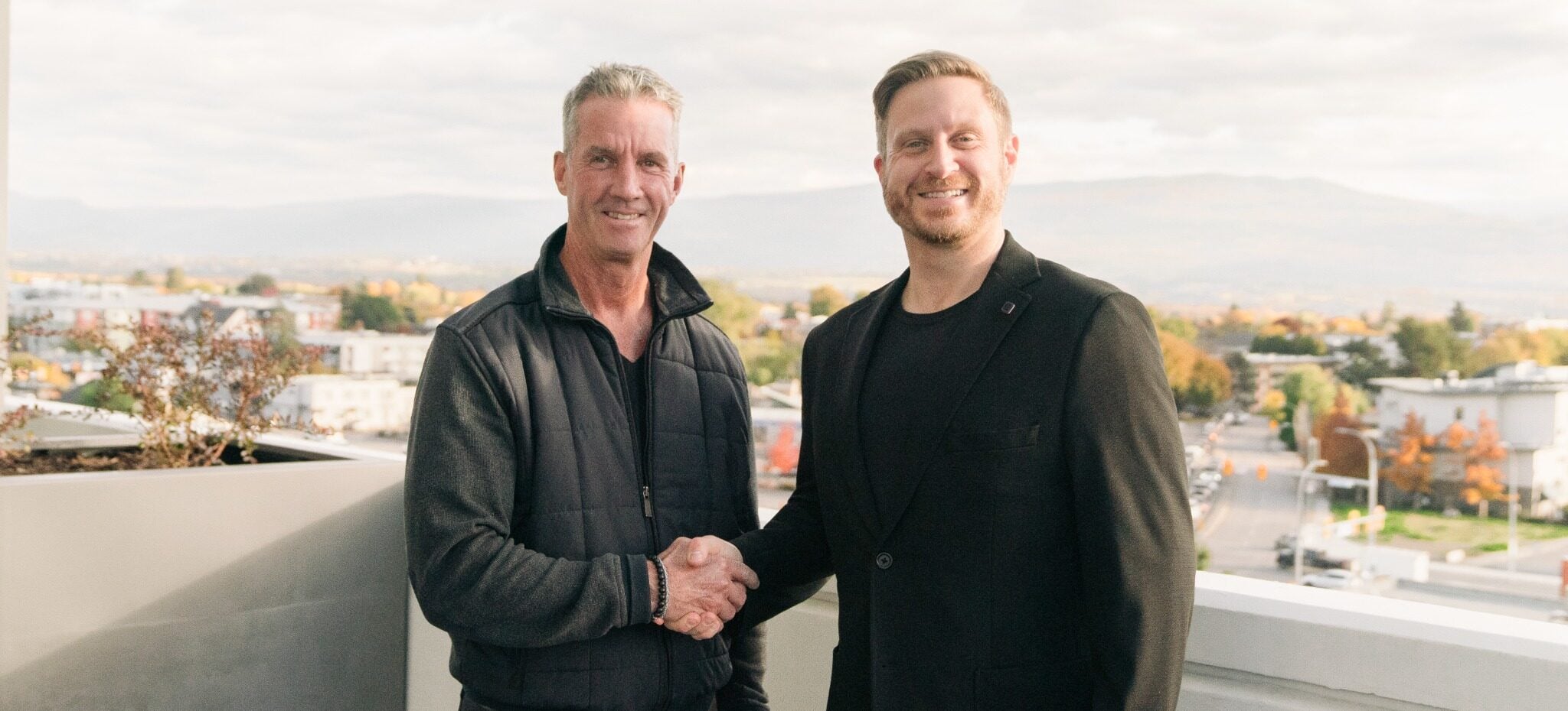 Two men shaking hands on a terrace to celebrate the Ace and Sutton partnership.